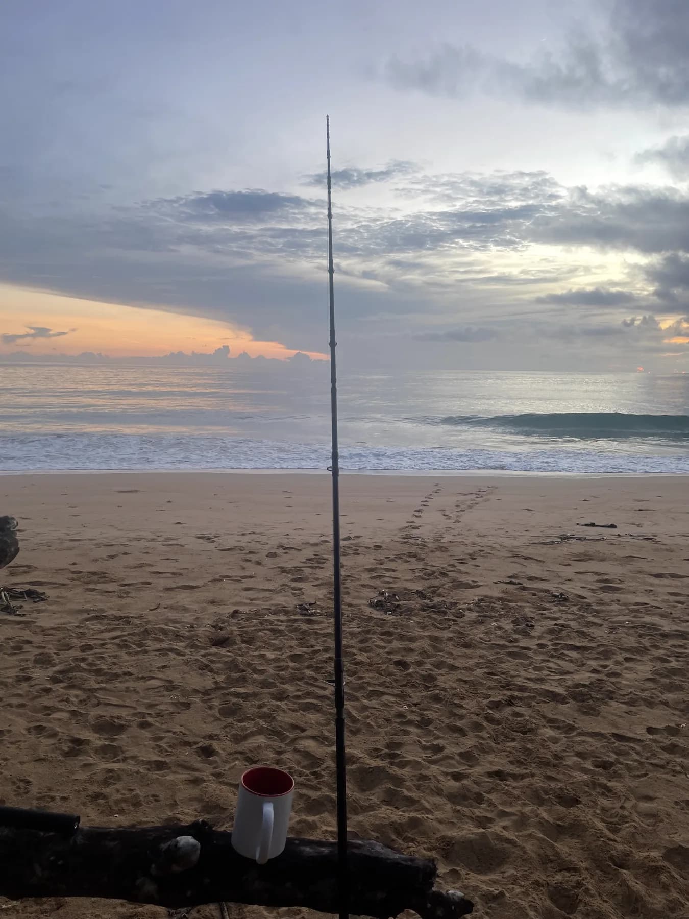 Canne de pêche plantée dans le sable face aux vagues au coucher du soleil, Caraïbes panaméennes