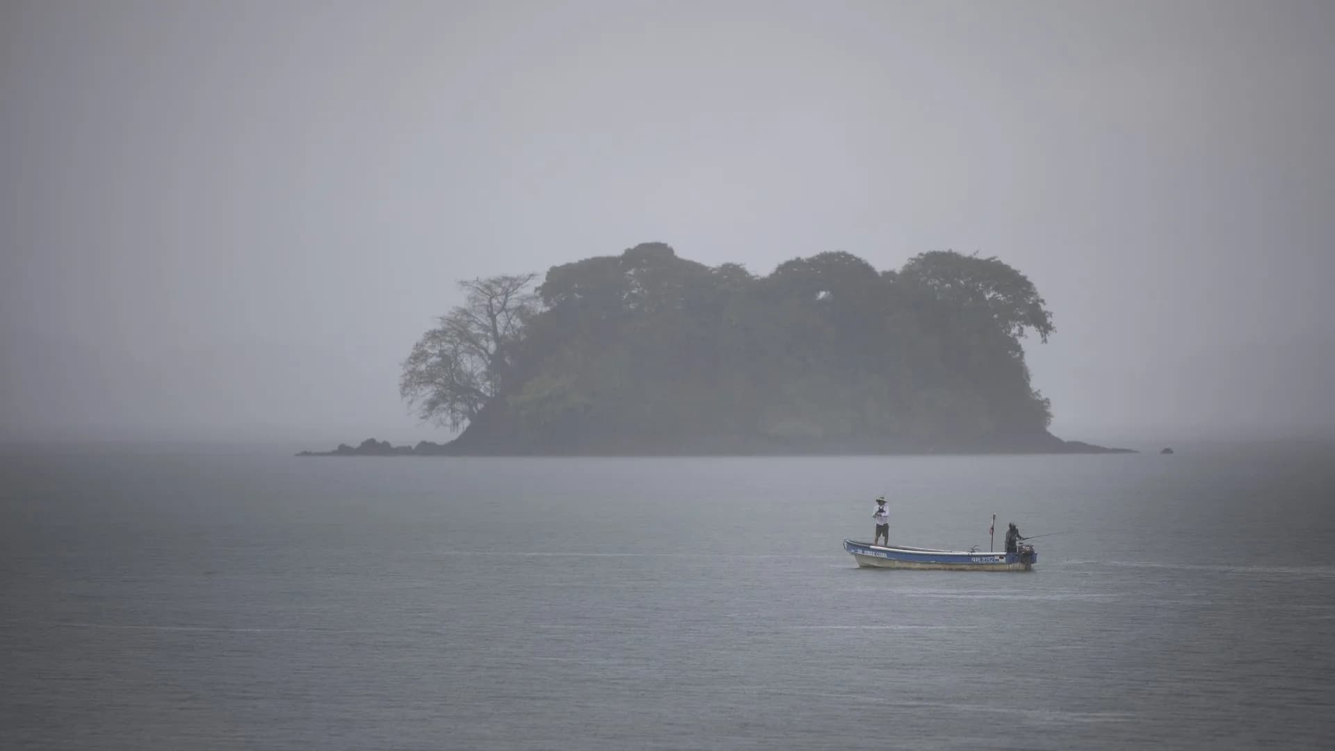 Pescadores en una barca bajo la bruma frente a una isla del golfo de Chiriquí
